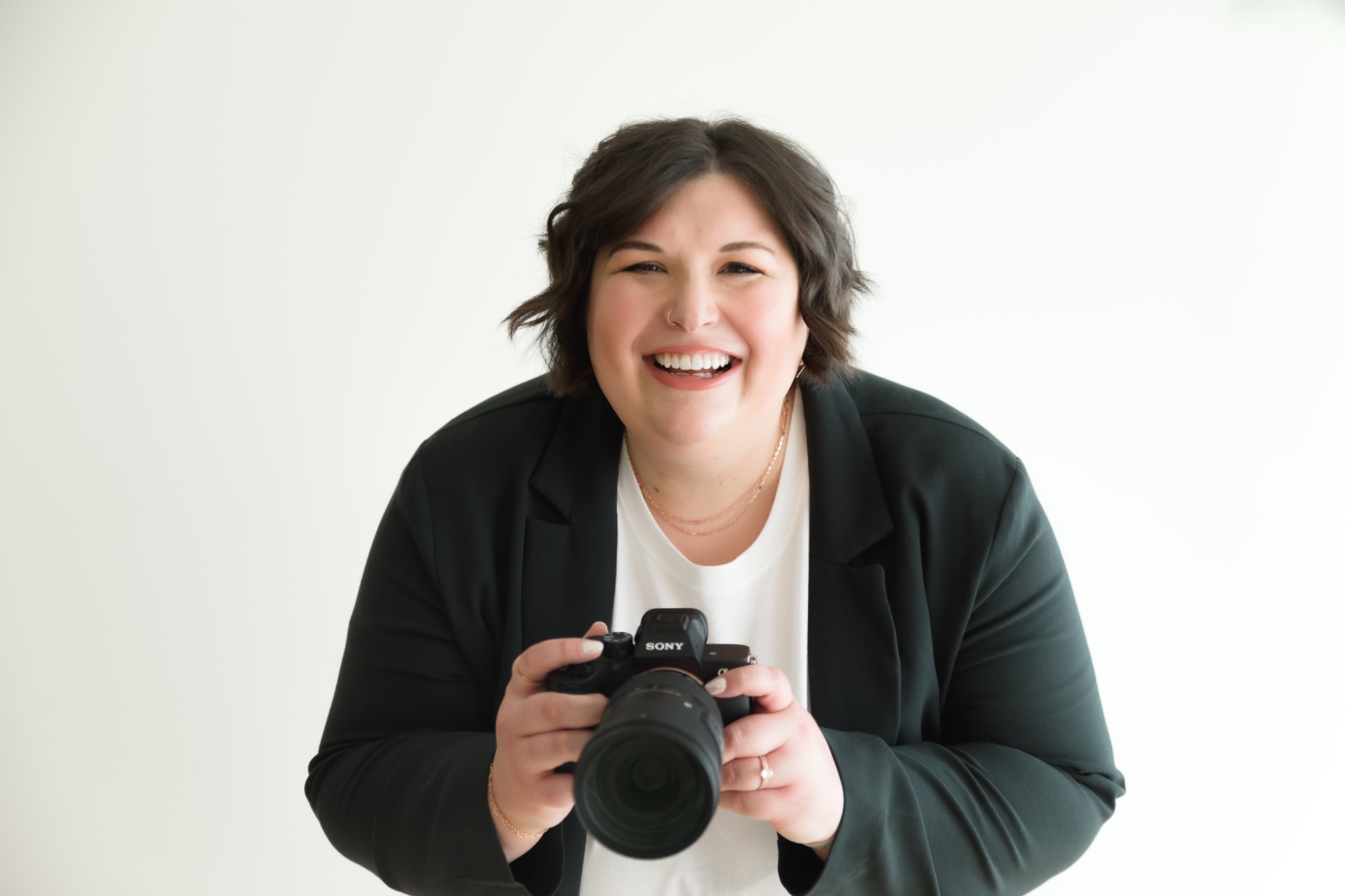Jess holding her camera in a black blazer