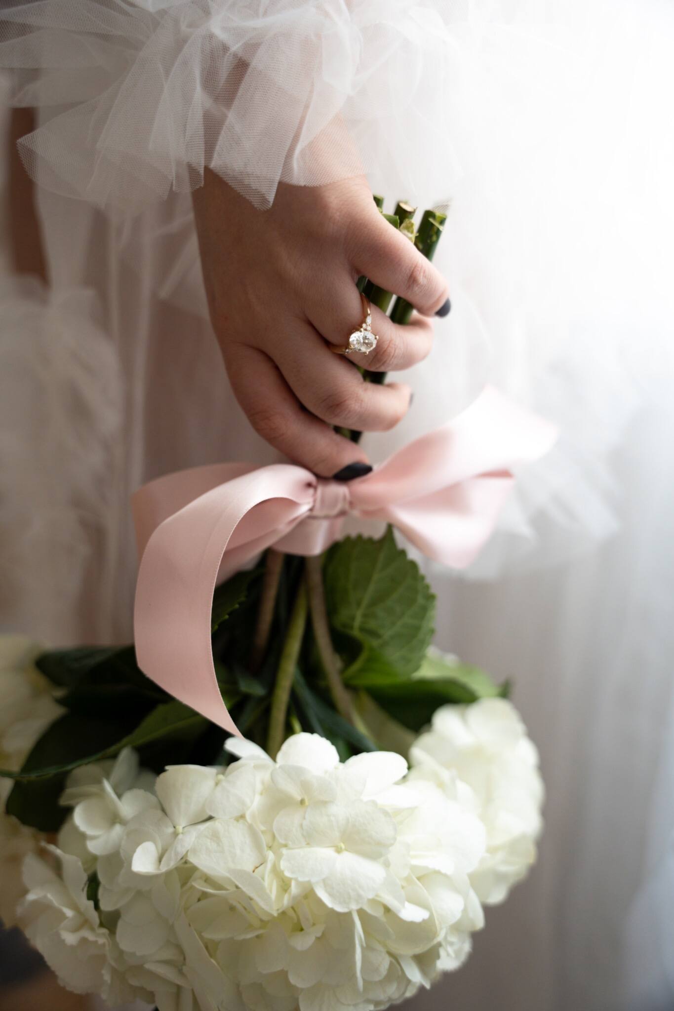 Bride holding a bouquet tied with a pink ribbon