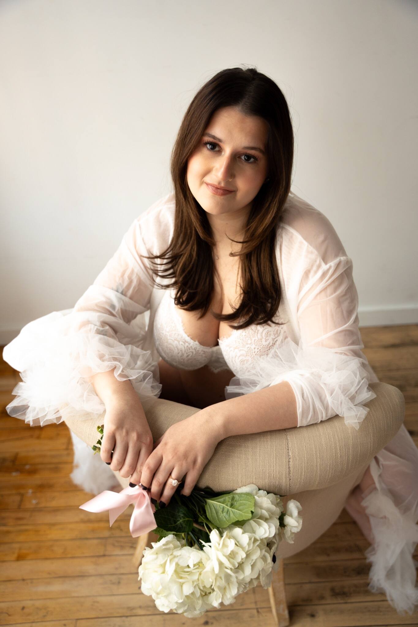 Woman seated in white lingerie and a sheer robe