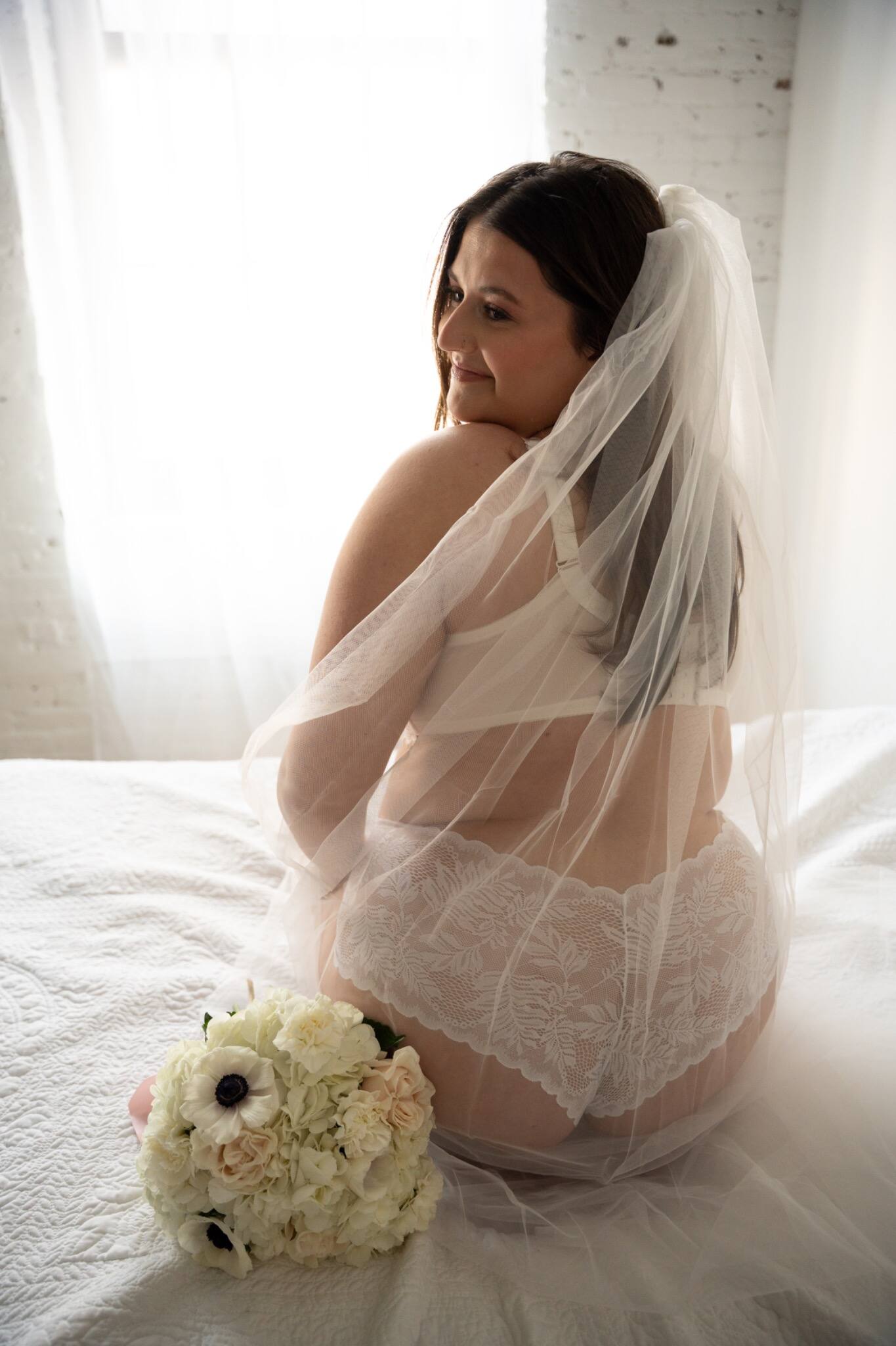 Woman wearing a sheer veil beside a white bouquet