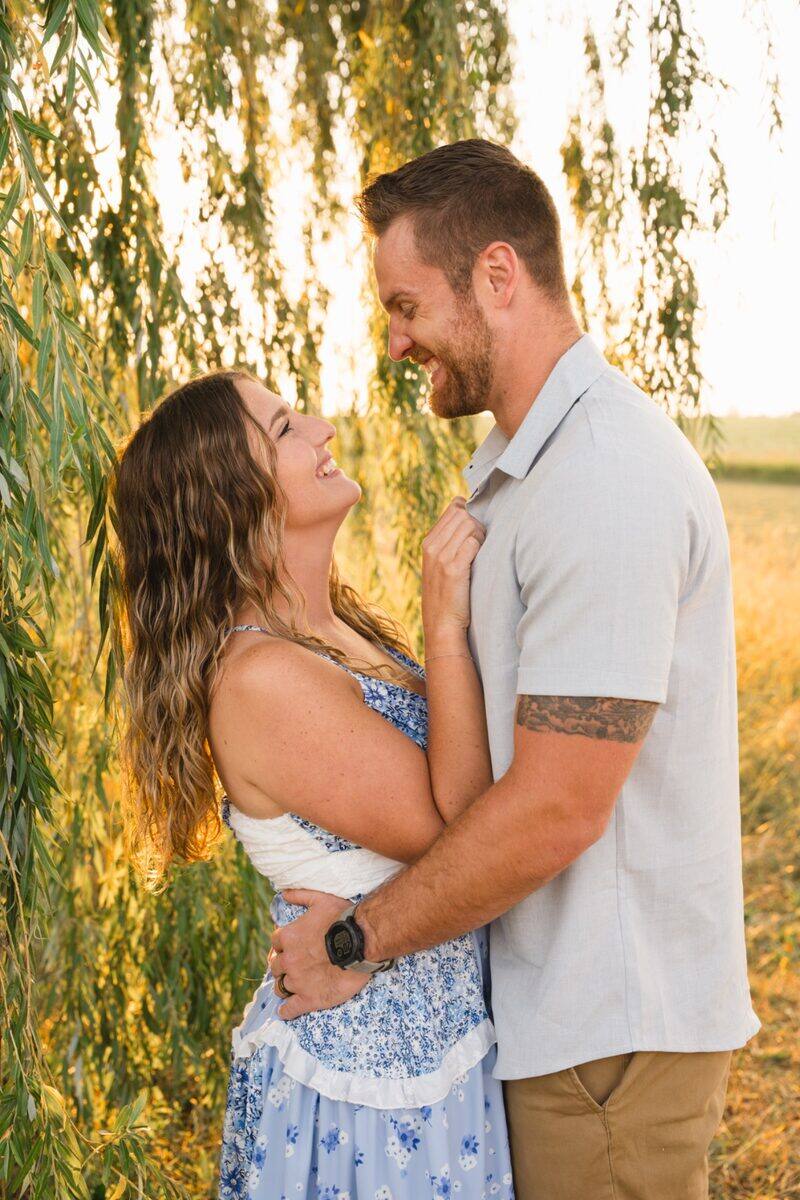 Couple laughing beneath a willow tree