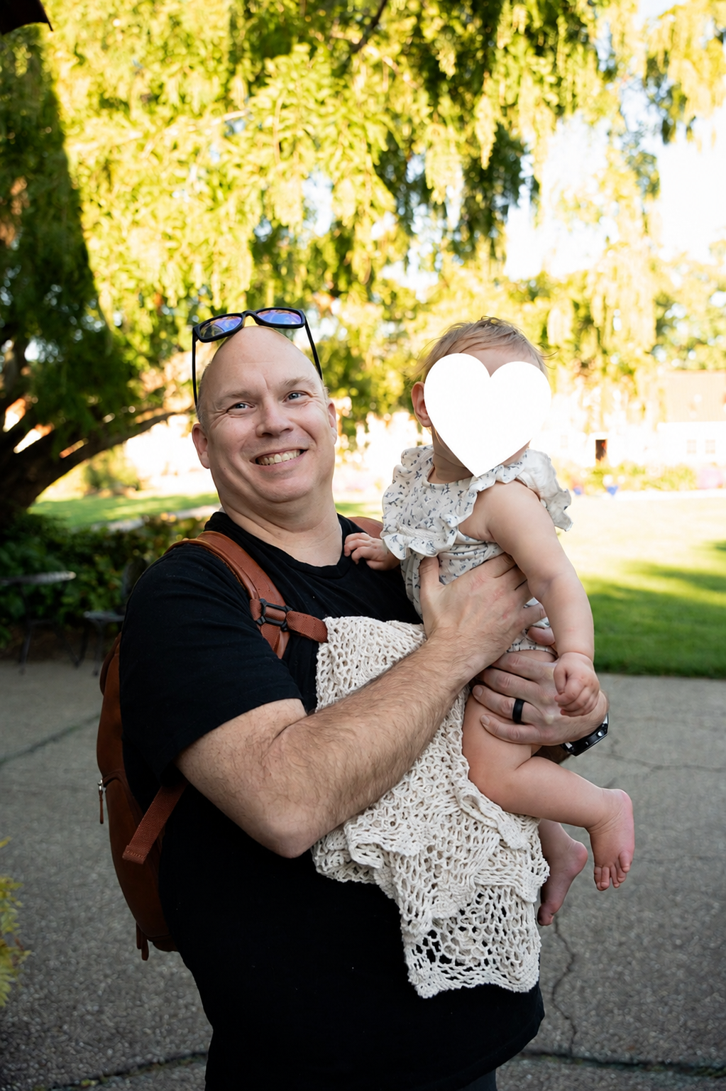 Chris holding a child whose face is covered with a white heart for privacy