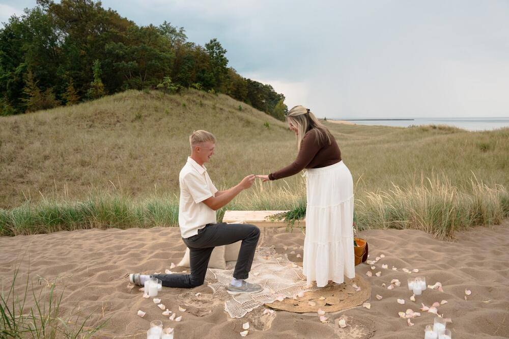Beach proposal surrounded by flower petals