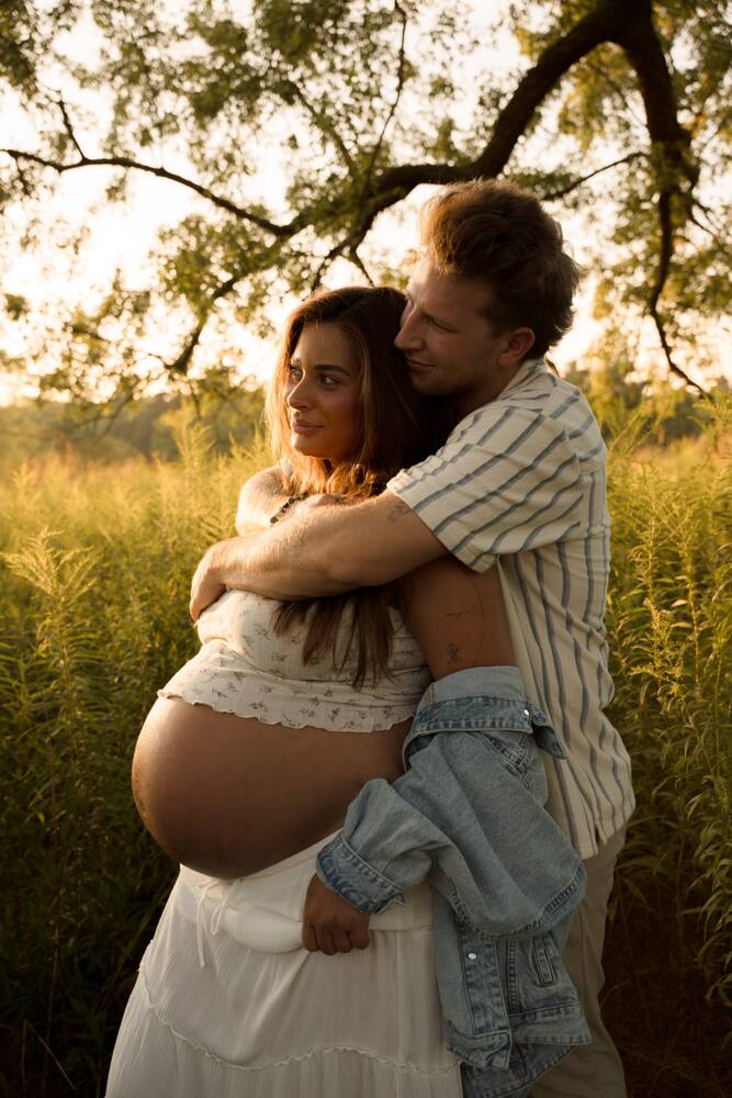 Expecting couple embracing outdoors