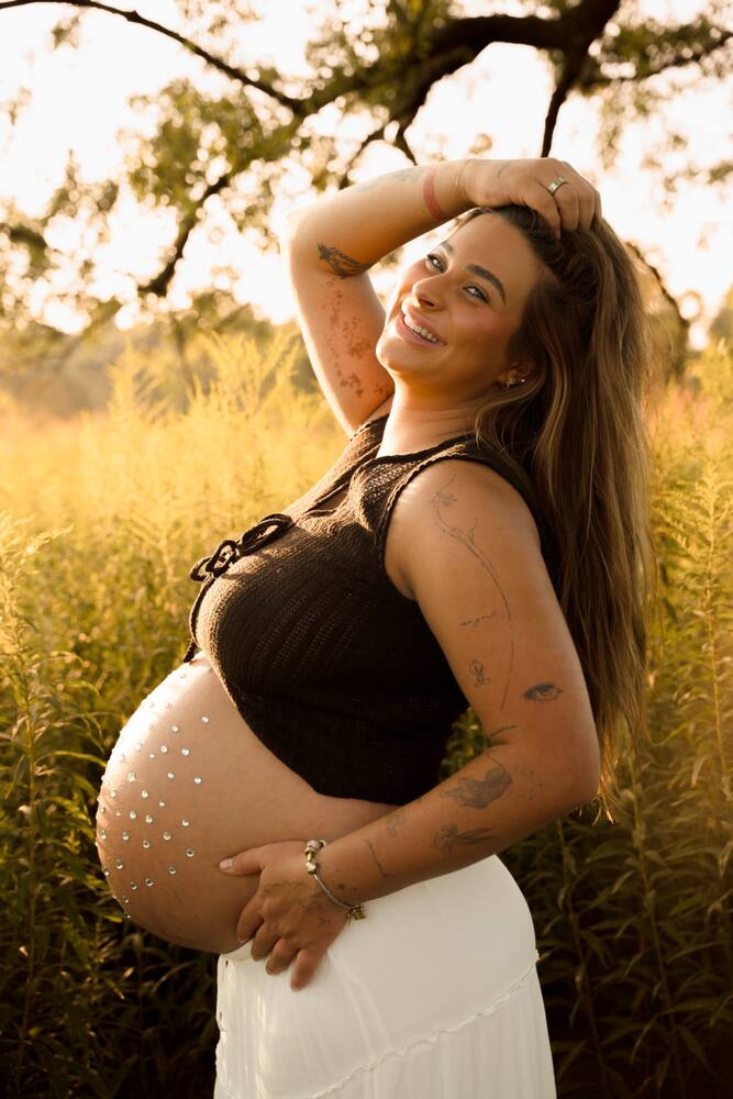 Sunlit maternity portrait in a field