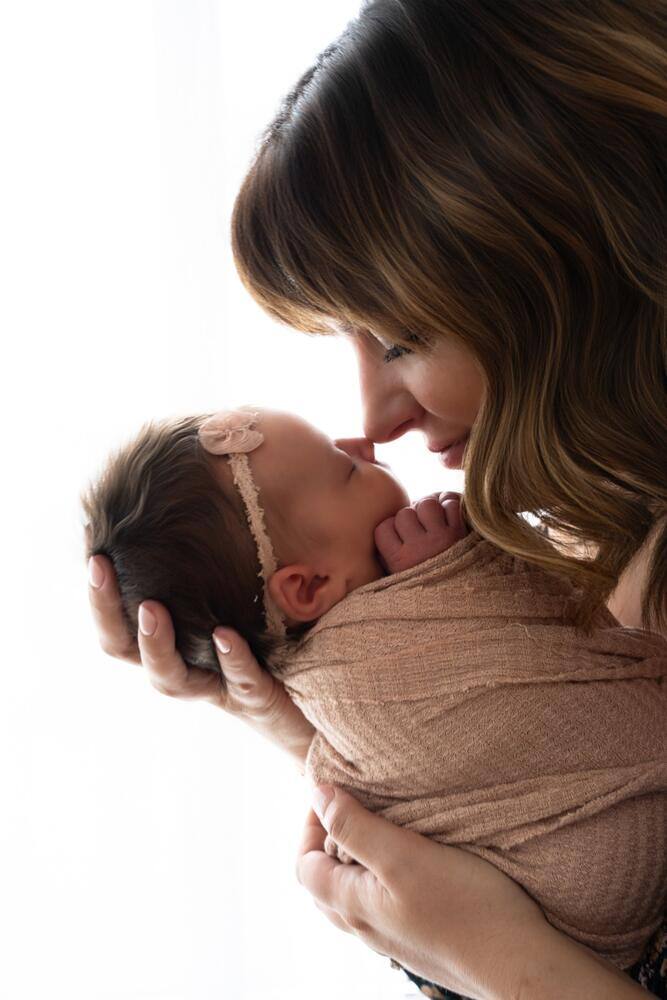 Mother holding her baby near a bright window