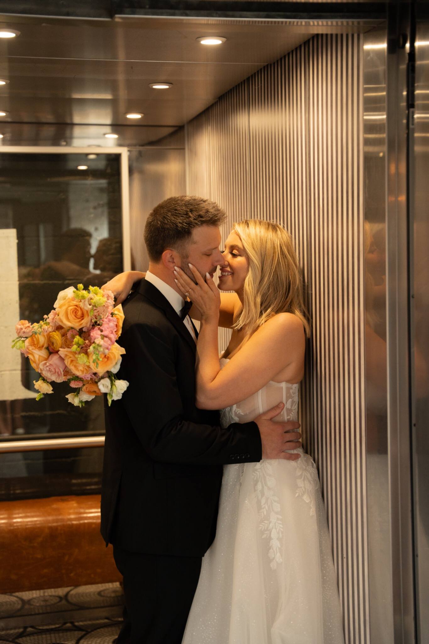 Newlyweds sharing a kiss in an art deco elevator