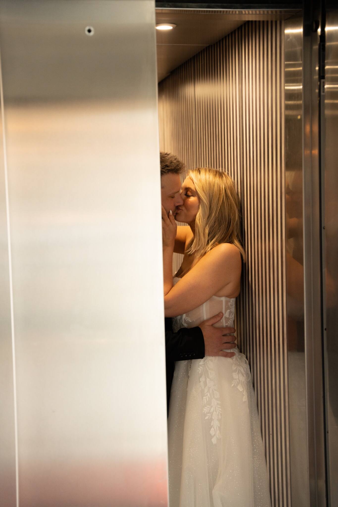A newlywed couple embracing in an elegant elevator