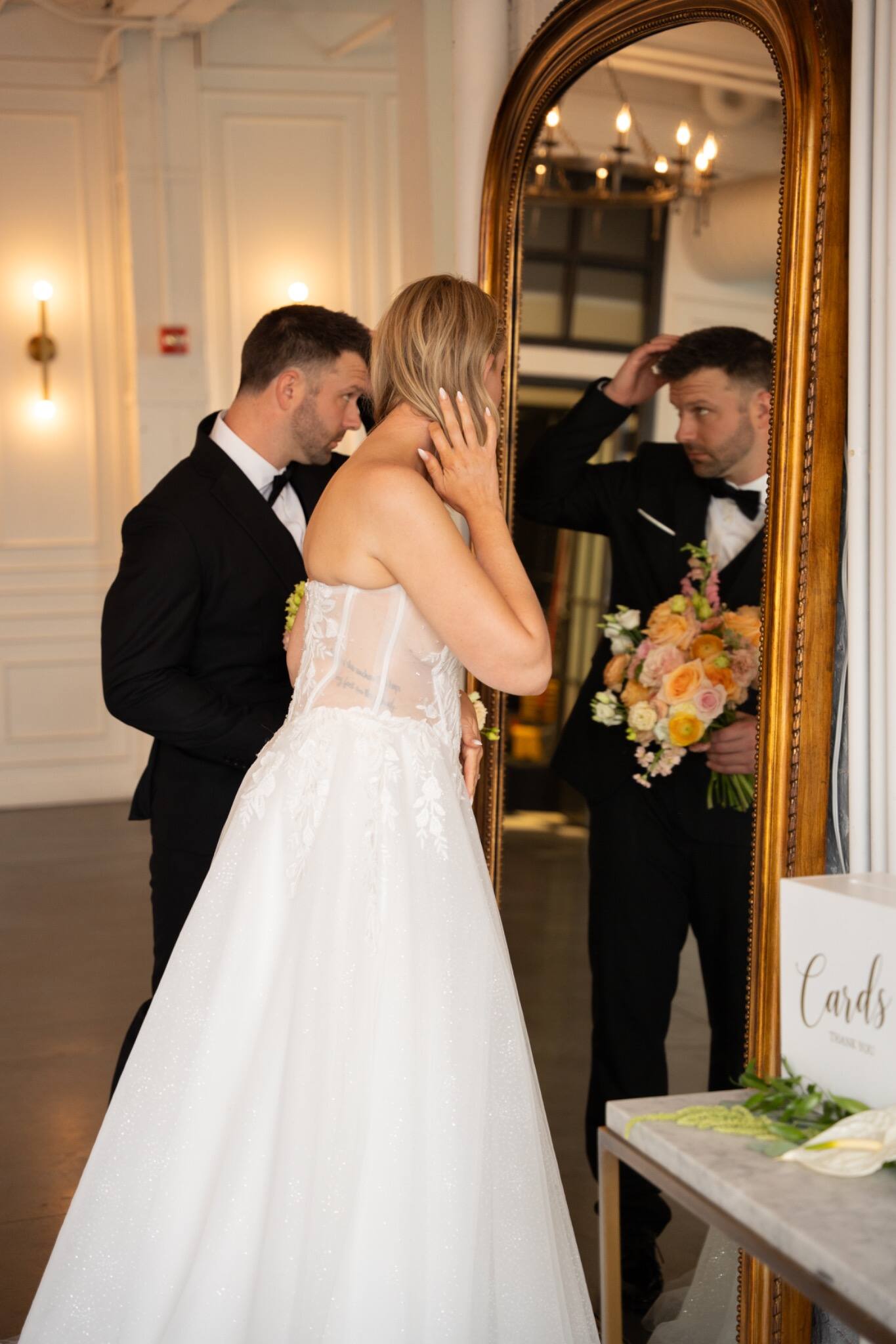 A bride and groom sharing a quiet moment beside a mirror