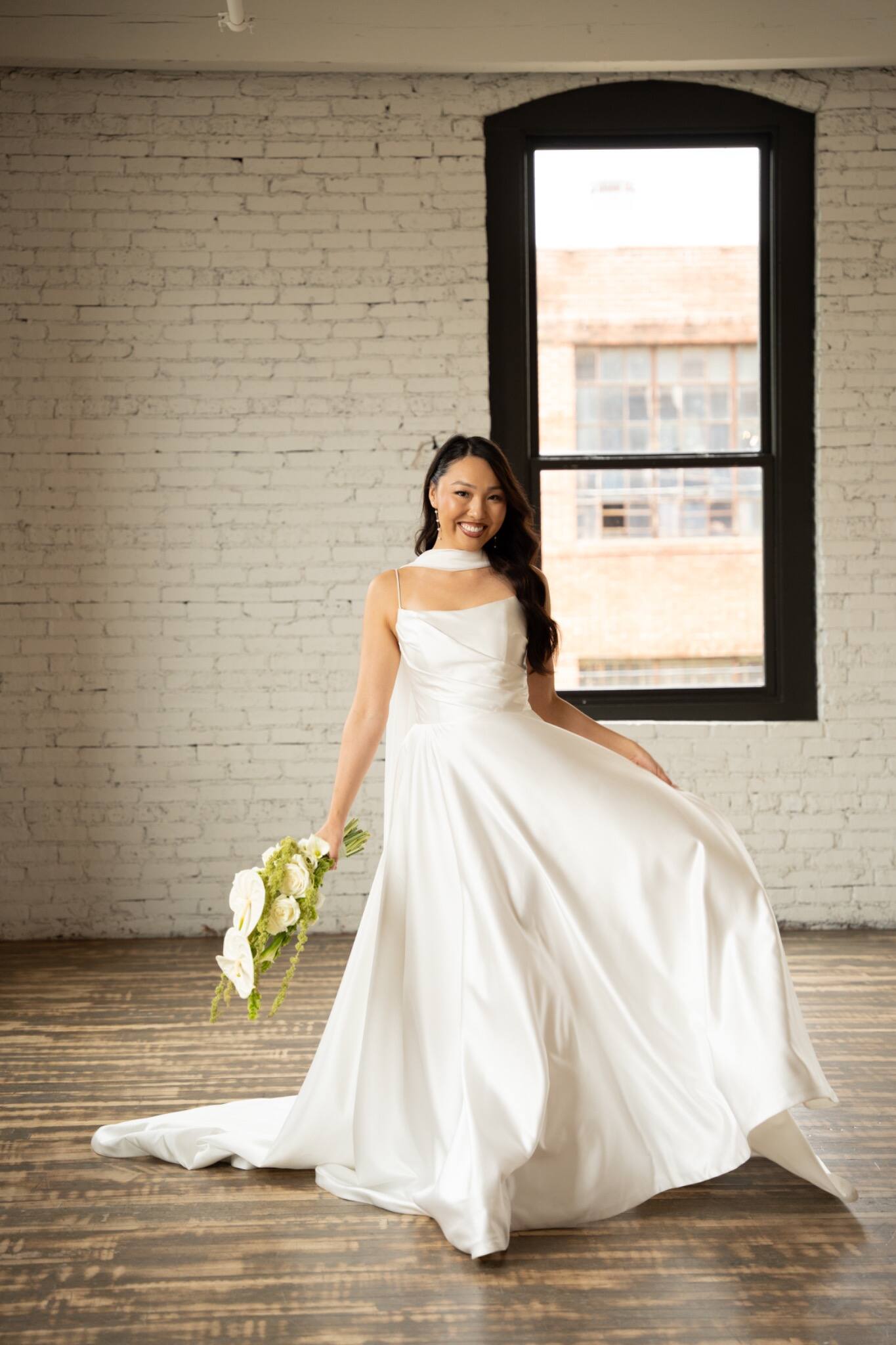 Full-length bridal portrait by an industrial window