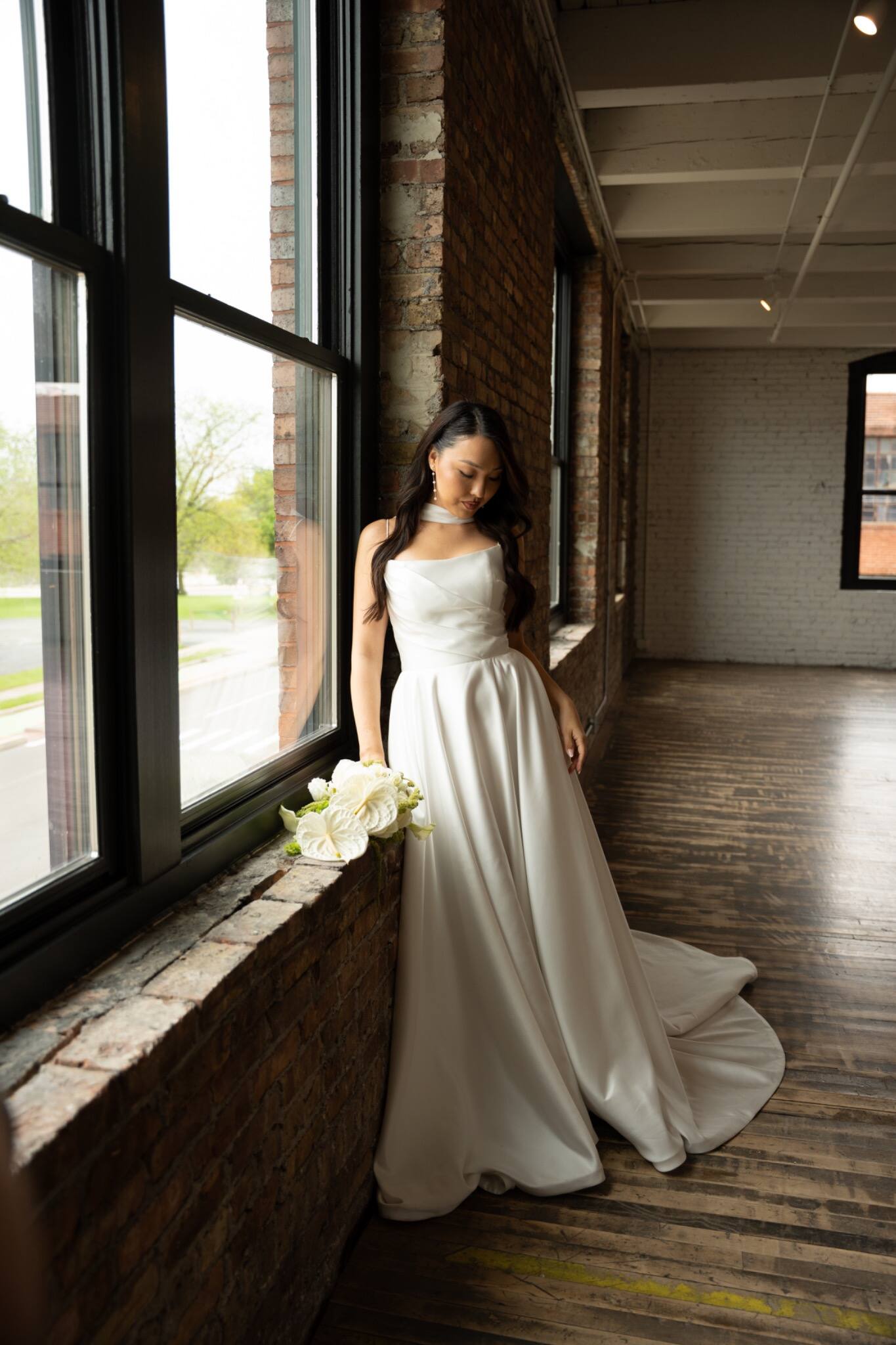 A bride posing between tall venue windows