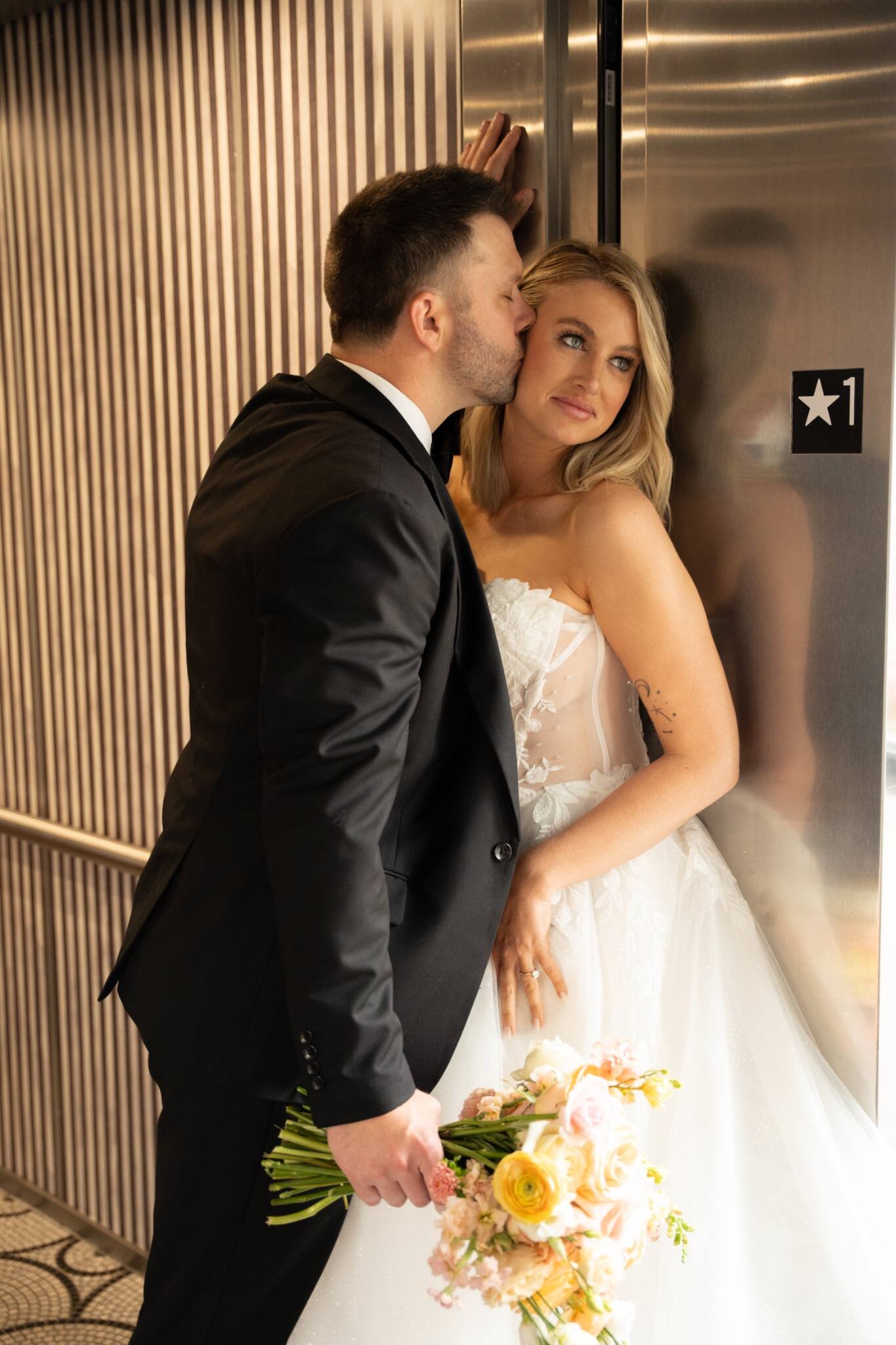 A wedding couple embracing in a vintage elevator