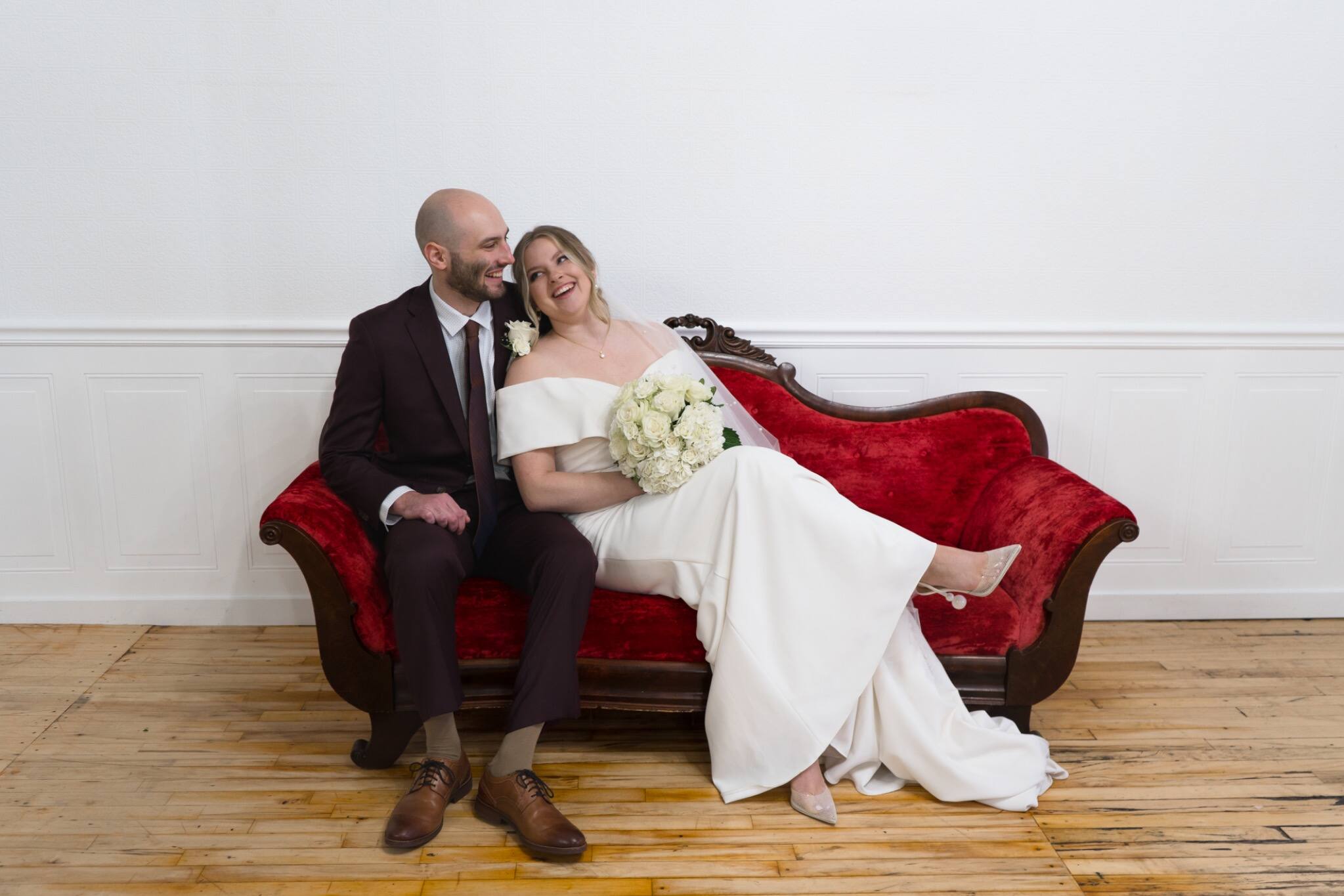 Newlyweds relaxing together on a red velvet settee