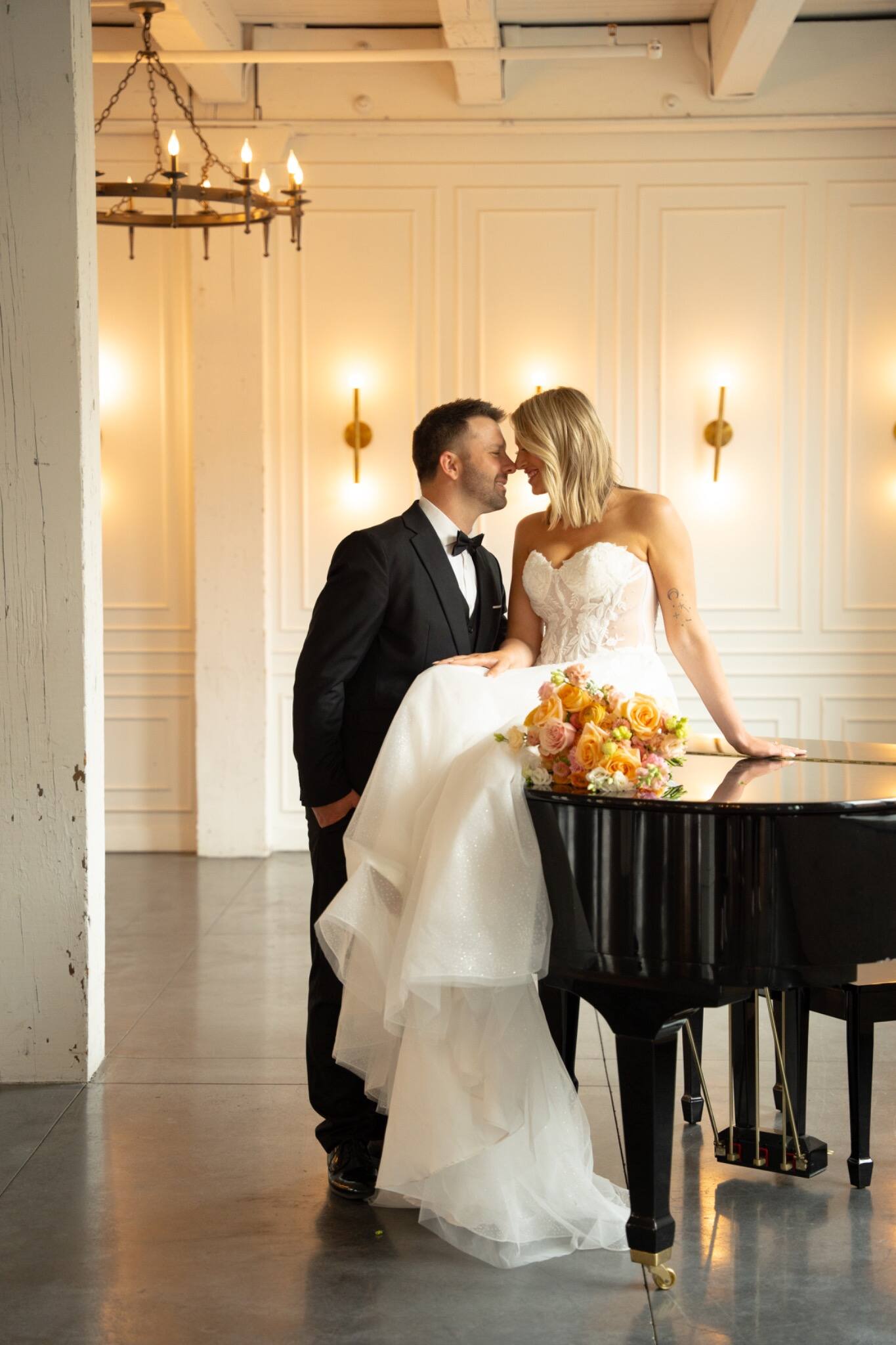 A bride and groom kissing beside a grand piano