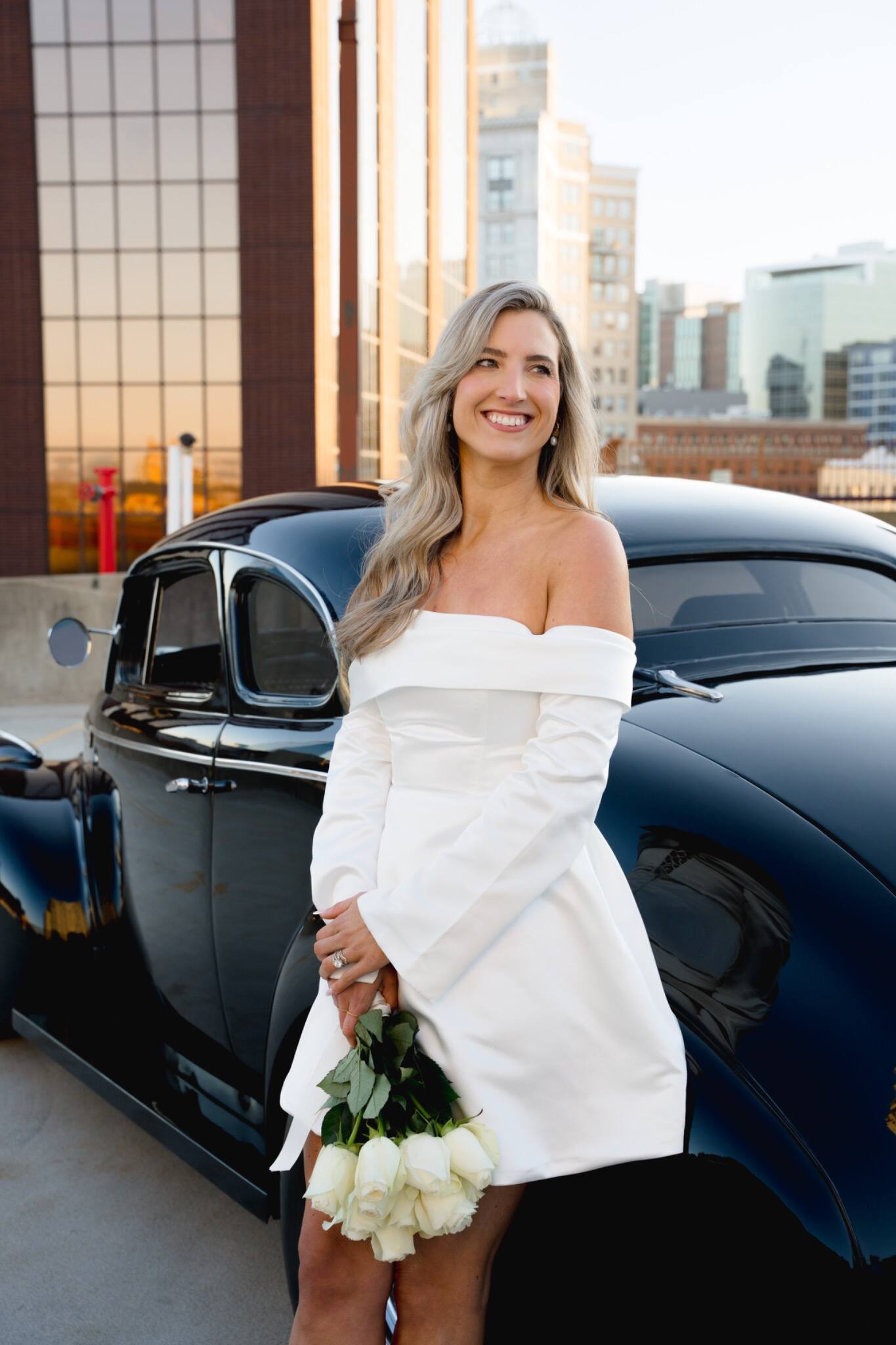 A bride posing in front of a classic car