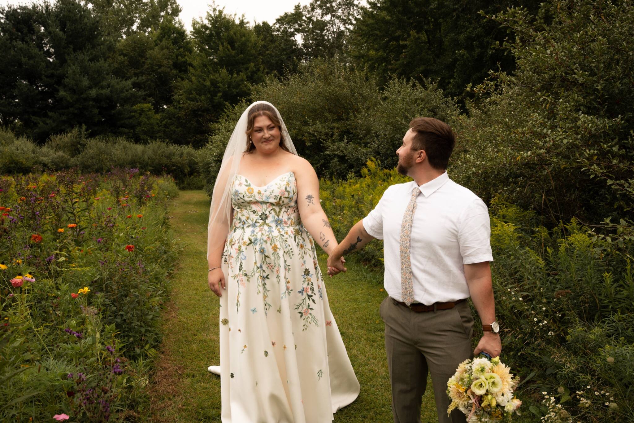 Newlyweds holding hands in a wide garden portrait