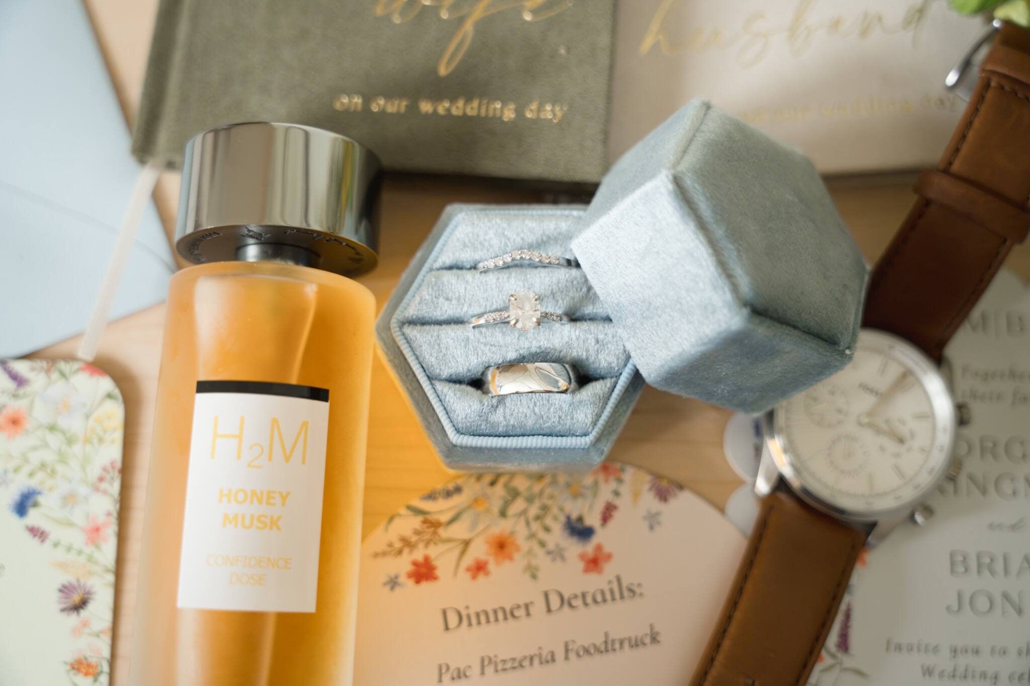Wedding-day details with rings, fragrance, and stationery