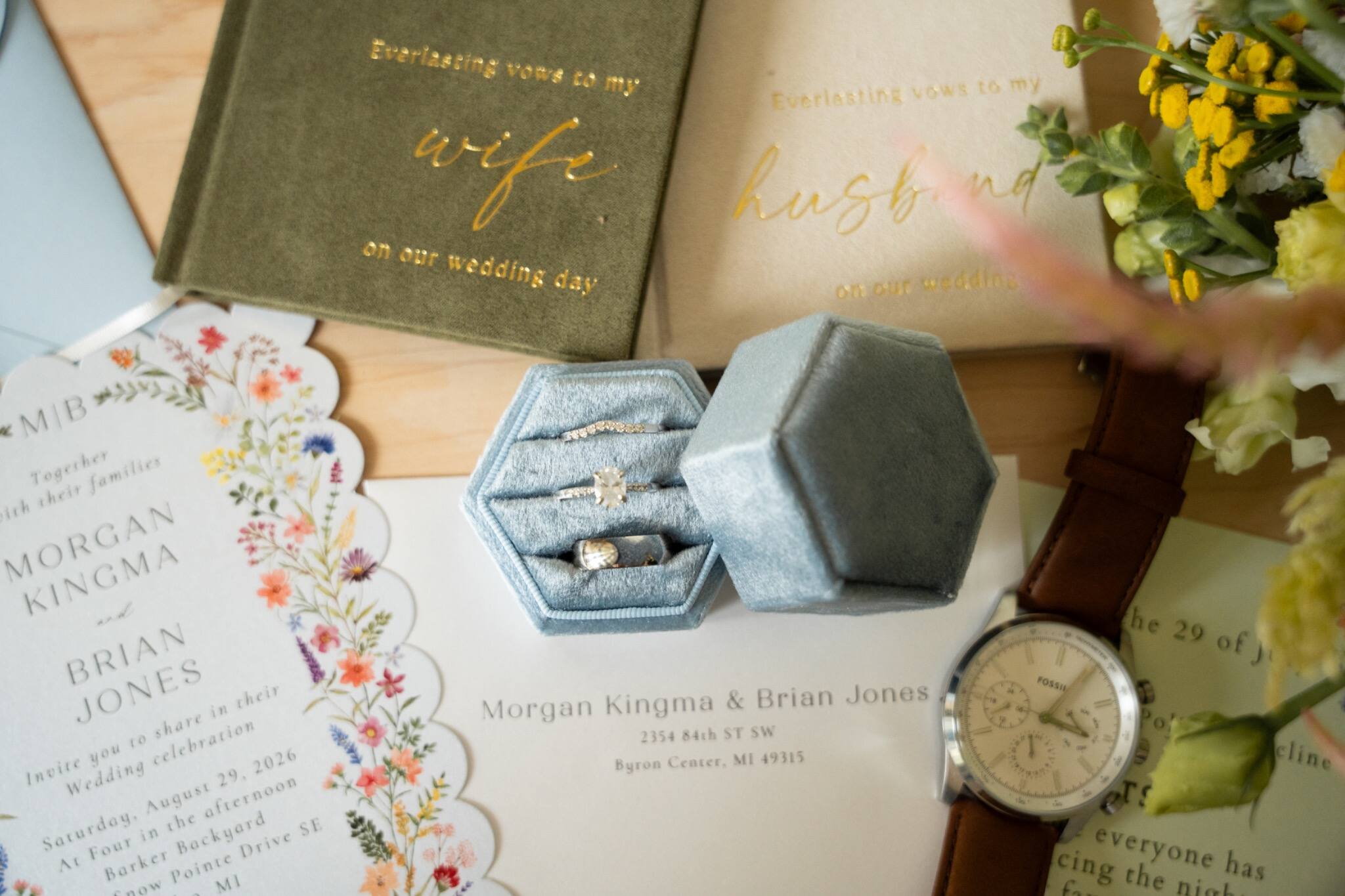 Wedding rings displayed with invitation suite and watch