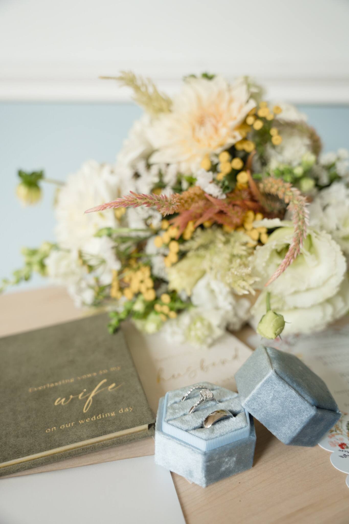 Wedding vow books, bouquet, and blue velvet ring boxes