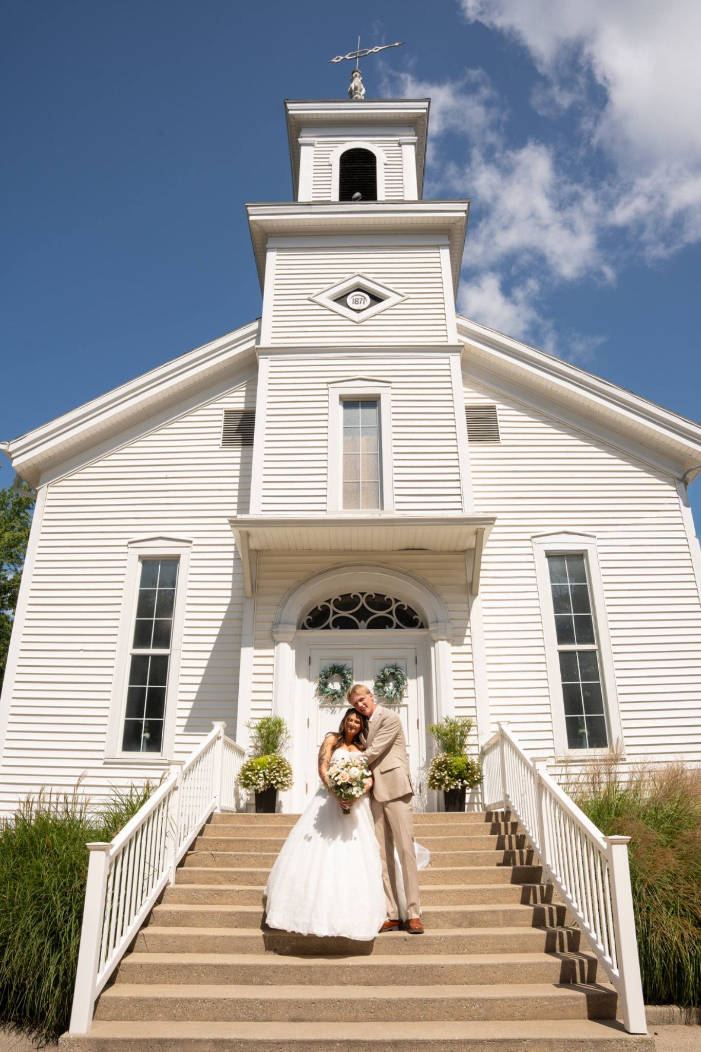 Newlyweds standing on the steps of a white church