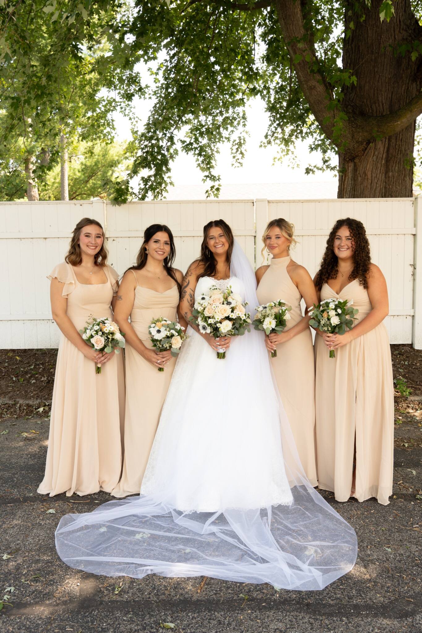 Bride and bridesmaids posing beneath a shade tree