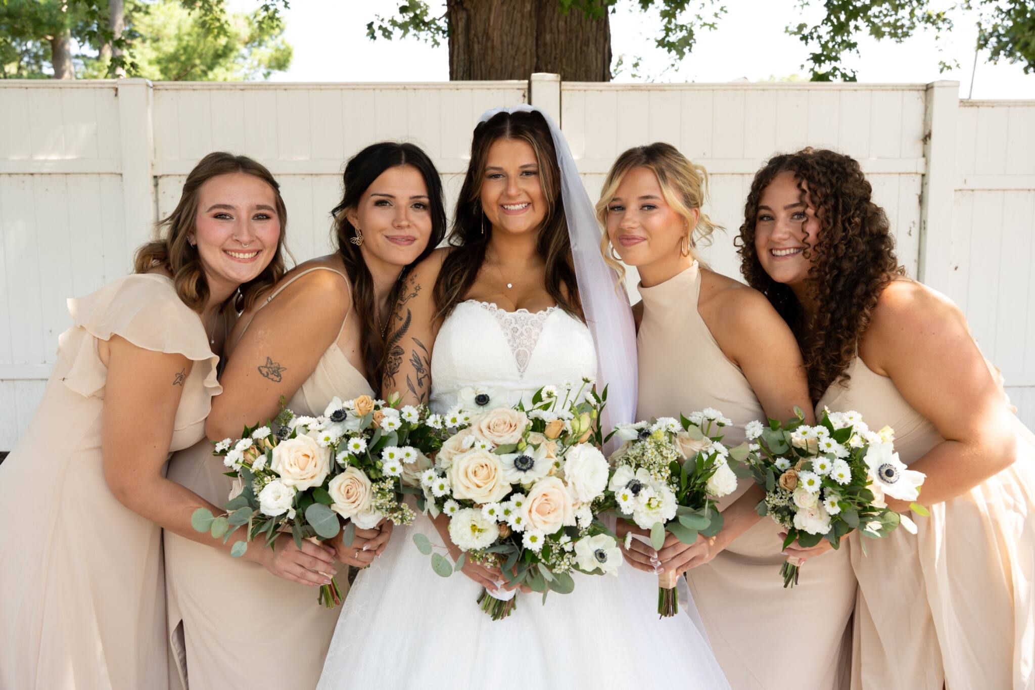 Bride and bridesmaids smiling together outdoors