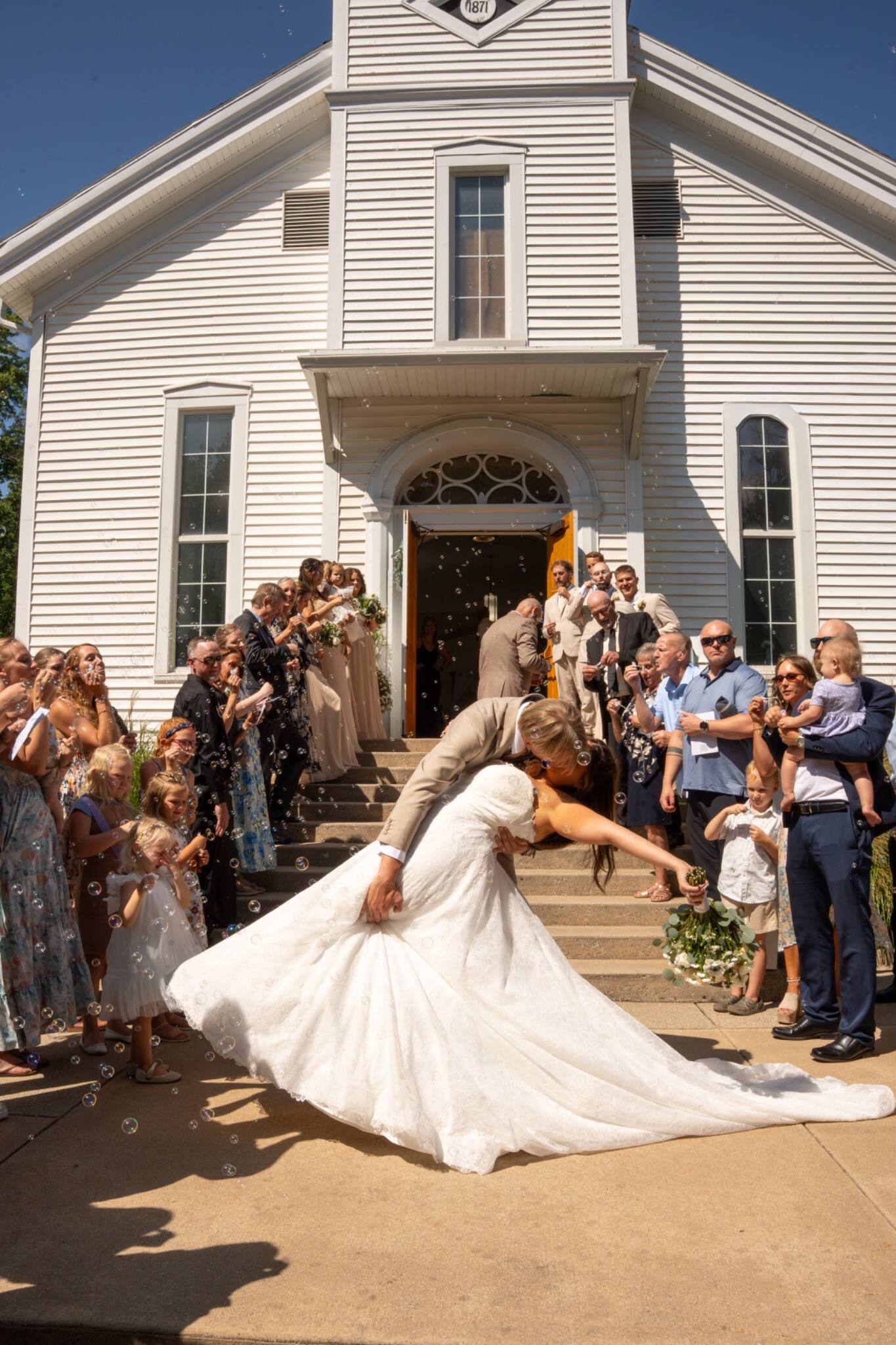 Newlyweds leaving the church through bubbles and cheers
