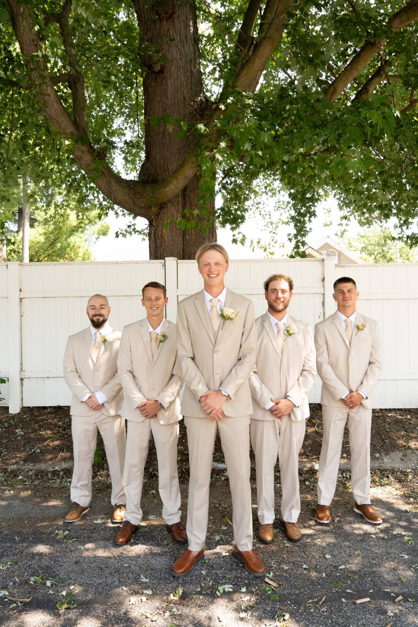 Groom and groomsmen posing beneath a large tree