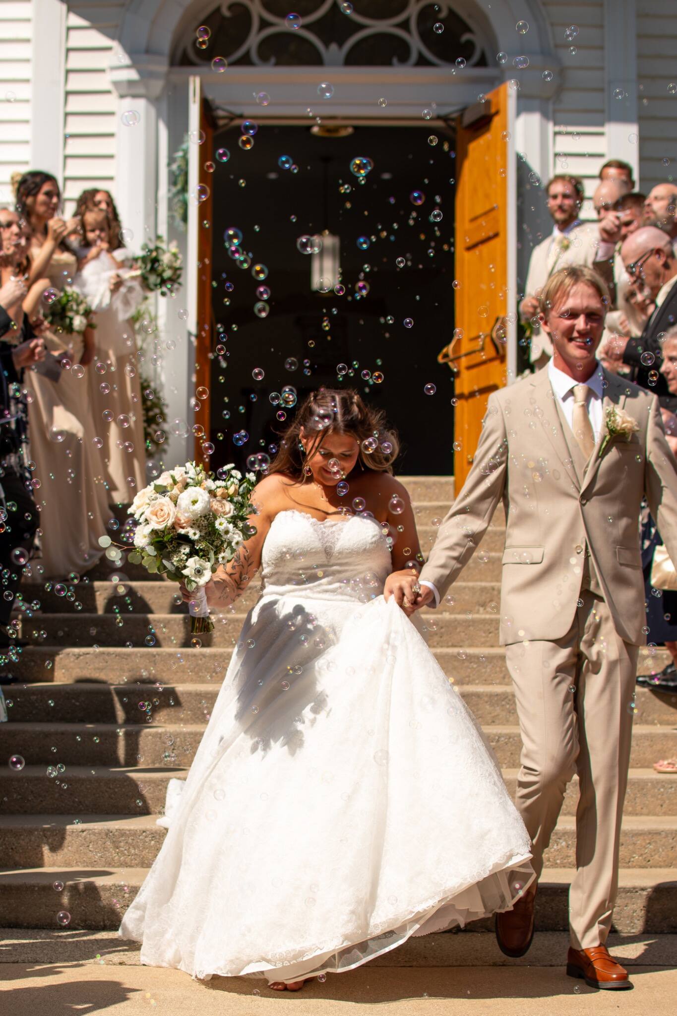 Newlyweds walking out of church through floating bubbles